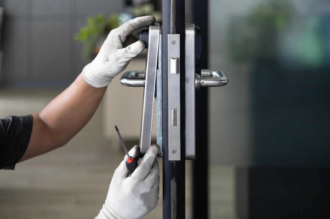 Handwerker, die mit einem Schraubenzieher das Türschloss im Zimmer reparieren
