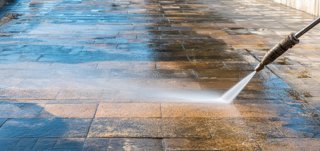Hochdruckreinigung der Terrassenoberfläche zur gründlichen Reinigung und Aufarbeitung in sonniger Außenumgebung mit einem Hochdruckwasserstrahl