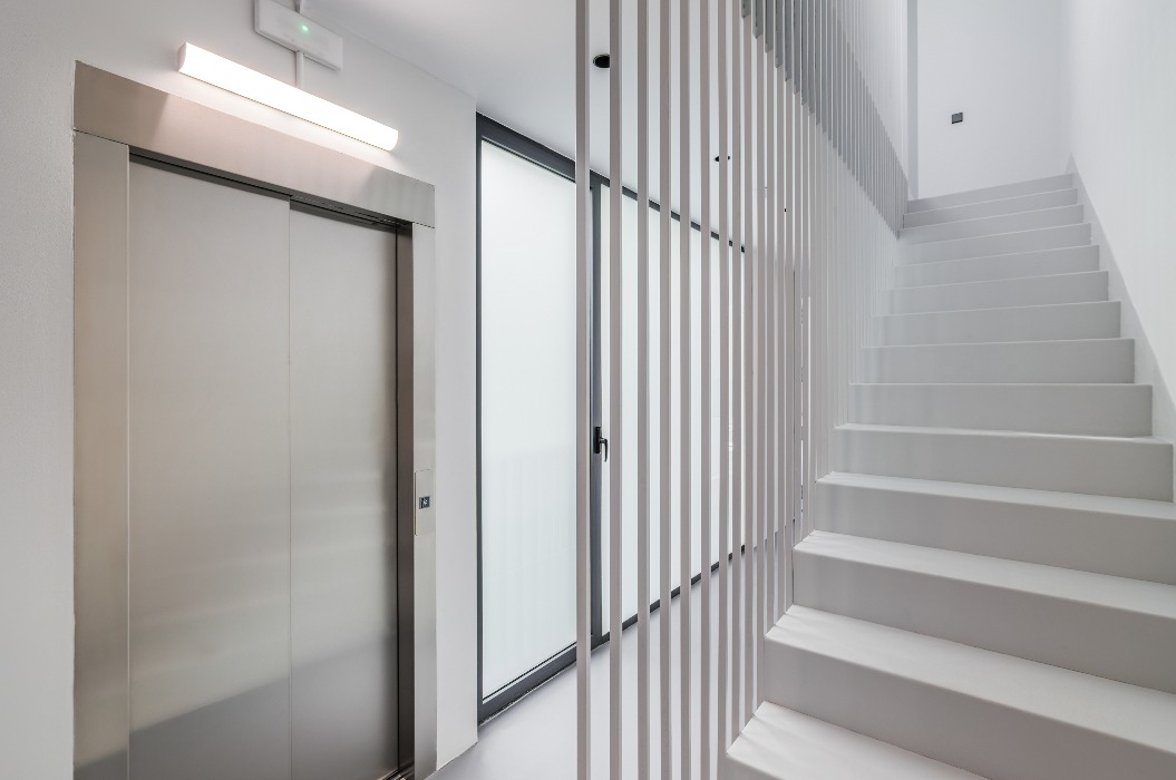 Moderner Hightech-Stil im Eingangsbereich eines neuen Wohnhauses oder Bürogebäudes mit Aufzug, Treppenhaus und Panoramafenster. Konzept für Neubauten mit einer ausgefeilten modernen Struktur