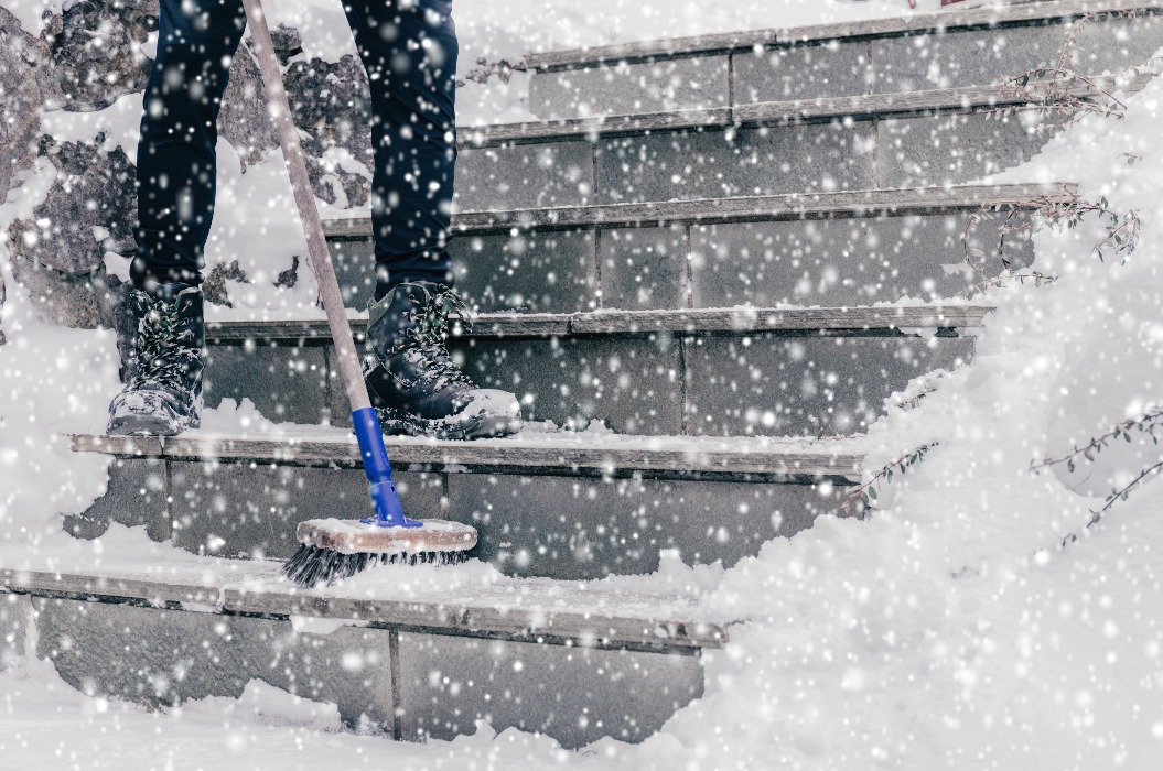 Schneeräumung auf der Treppe zum Haus nach Schneefällen